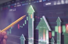 main tenant un crayon devant un visuel boursier (© Shutterstock)